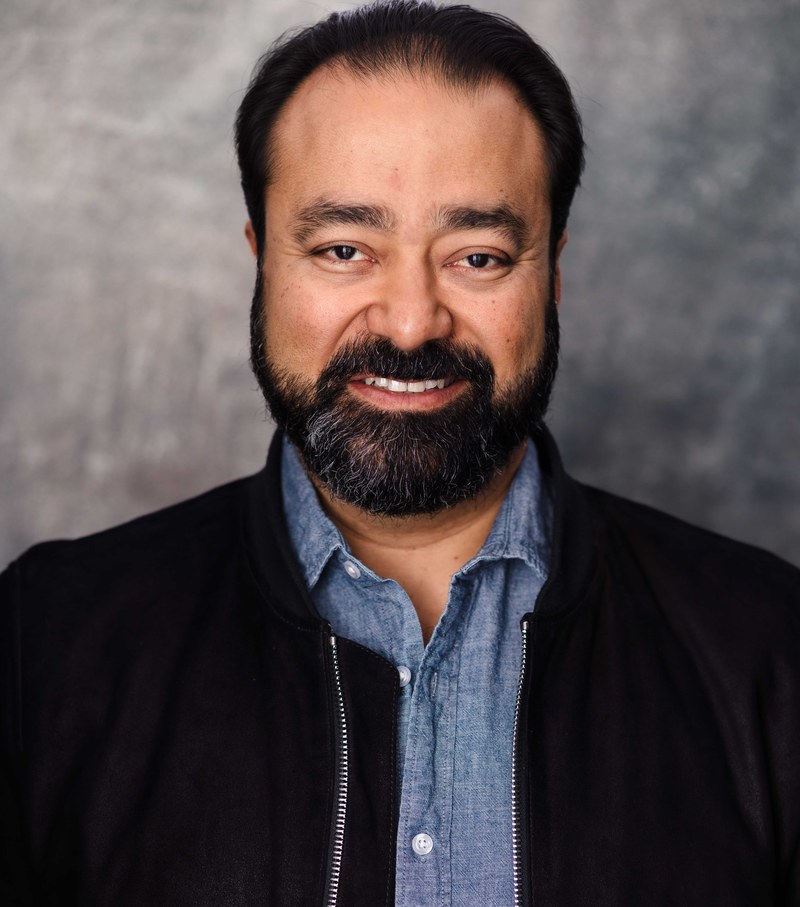 Gautam Kannan, headshot in black jacket and chambray shirt, smiling