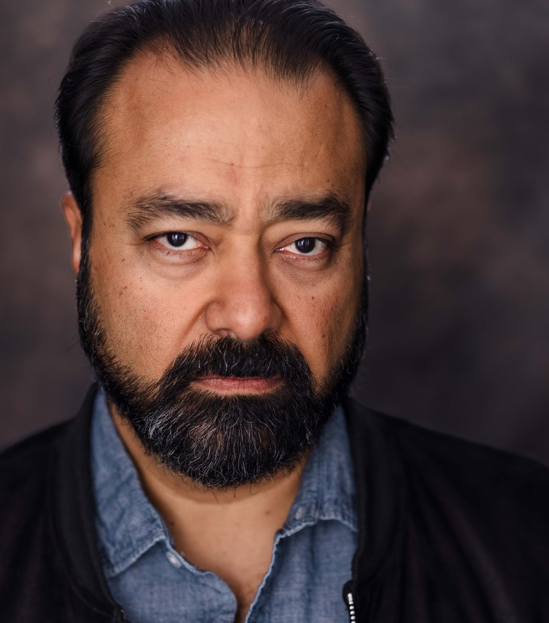Gautam Kannan, headshot in black jacket and chambray shirt, serious
